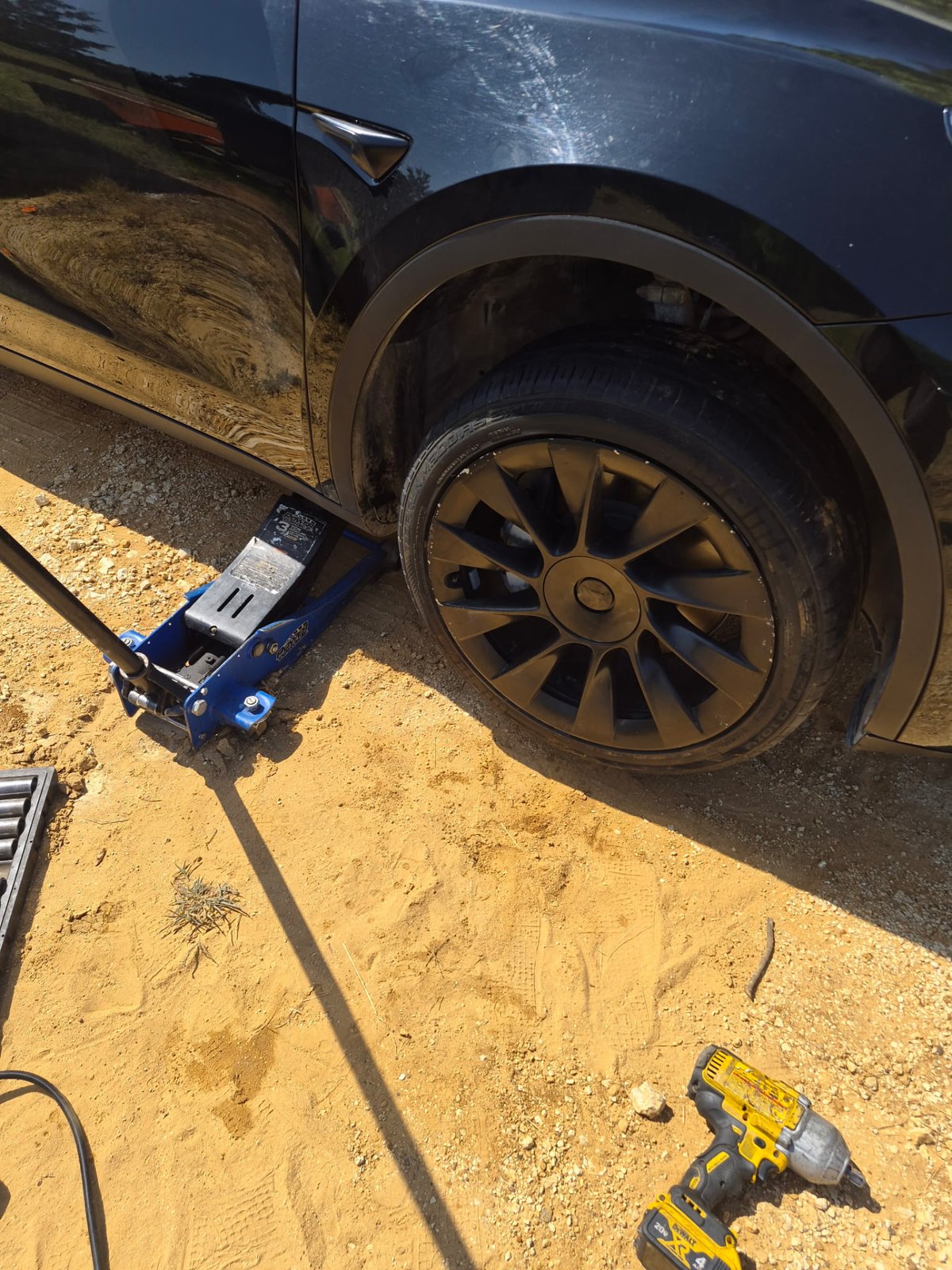 Close-up of the black Tesla Model Y 19-inch Gemini wheel removed, brake rotor and impact wrench visible during a DFW driveway tire service Close-up of the black Tesla Model Y 19-inch Gemini wheel removed, brake rotor and impact wrench visible during a DFW driveway tire service