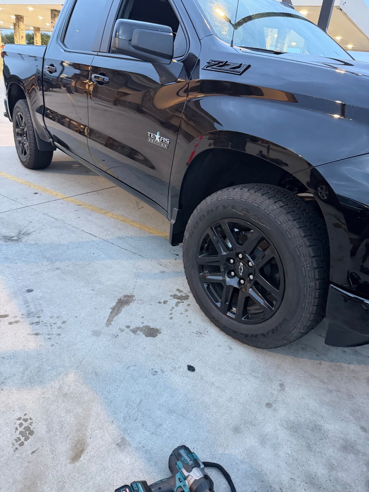 Black Chevrolet Silverado with a cordless impact wrench staged beside the front wheel during mobile tire service by All Hours Roadside
