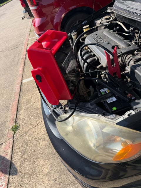 Red commercial jump pack clamped to a Hyundai 12V battery on S. Cooper Street in Arlington TX with a red Ford F-150 parked behind — All Hours Roadside 24/7 mobile jump start