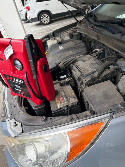 Hyundai SUV with dead battery being jump-started in Arlington TX using a Clore JNC950 Jump-N-Carry booster pack — All Hours Roadside same-hour mobile service