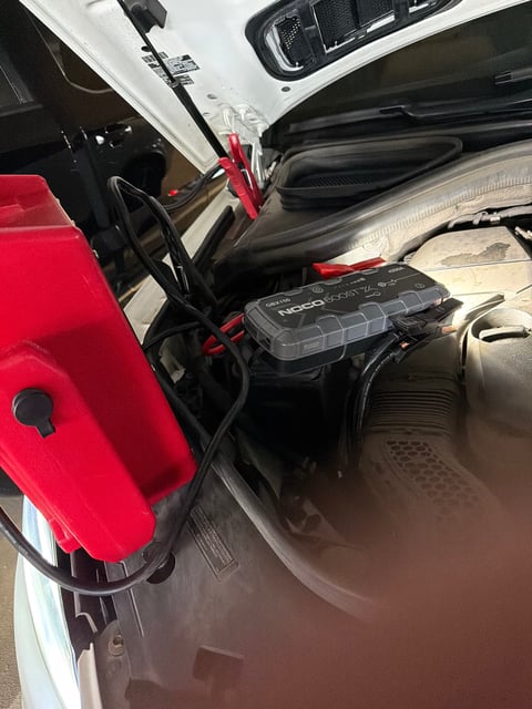 NOCO Boost X GBX155 4250A lithium jump starter clamped to a 12V battery under the hood during a roadside jump start in Mansfield TX — All Hours Roadside mobile battery boost