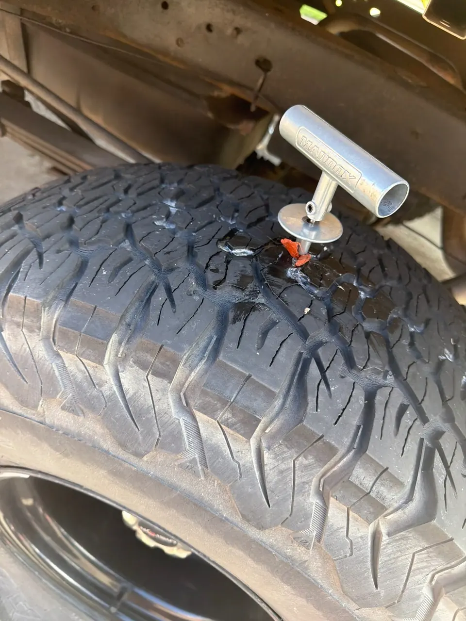 Plug tool inserting a repair plug into a truck tire during an on-site tire repair service